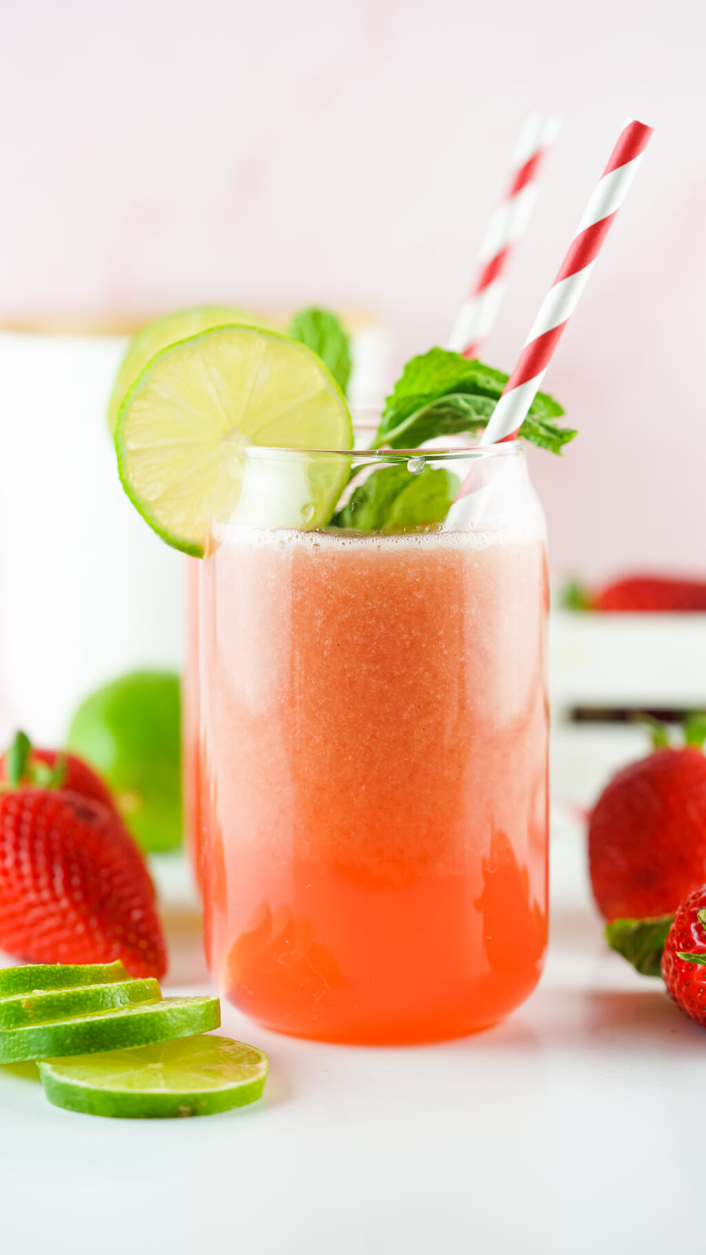 strawberry agua fresca in a tall clear glass with lime slice and striped straw