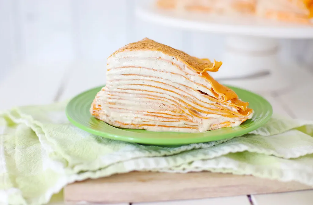 small slice of pumpkin spice crepe cake on green plate