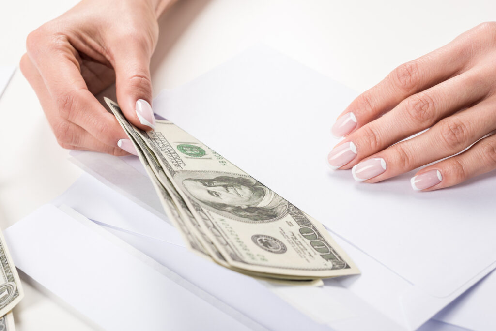 woman stuffing envelope with cash for 100 envelope challenge