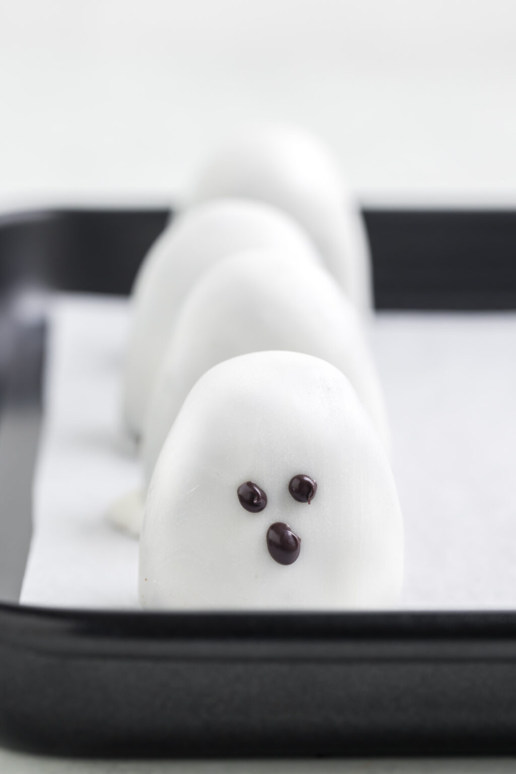 ghost oreo truffles with face drawn on in black melting candy