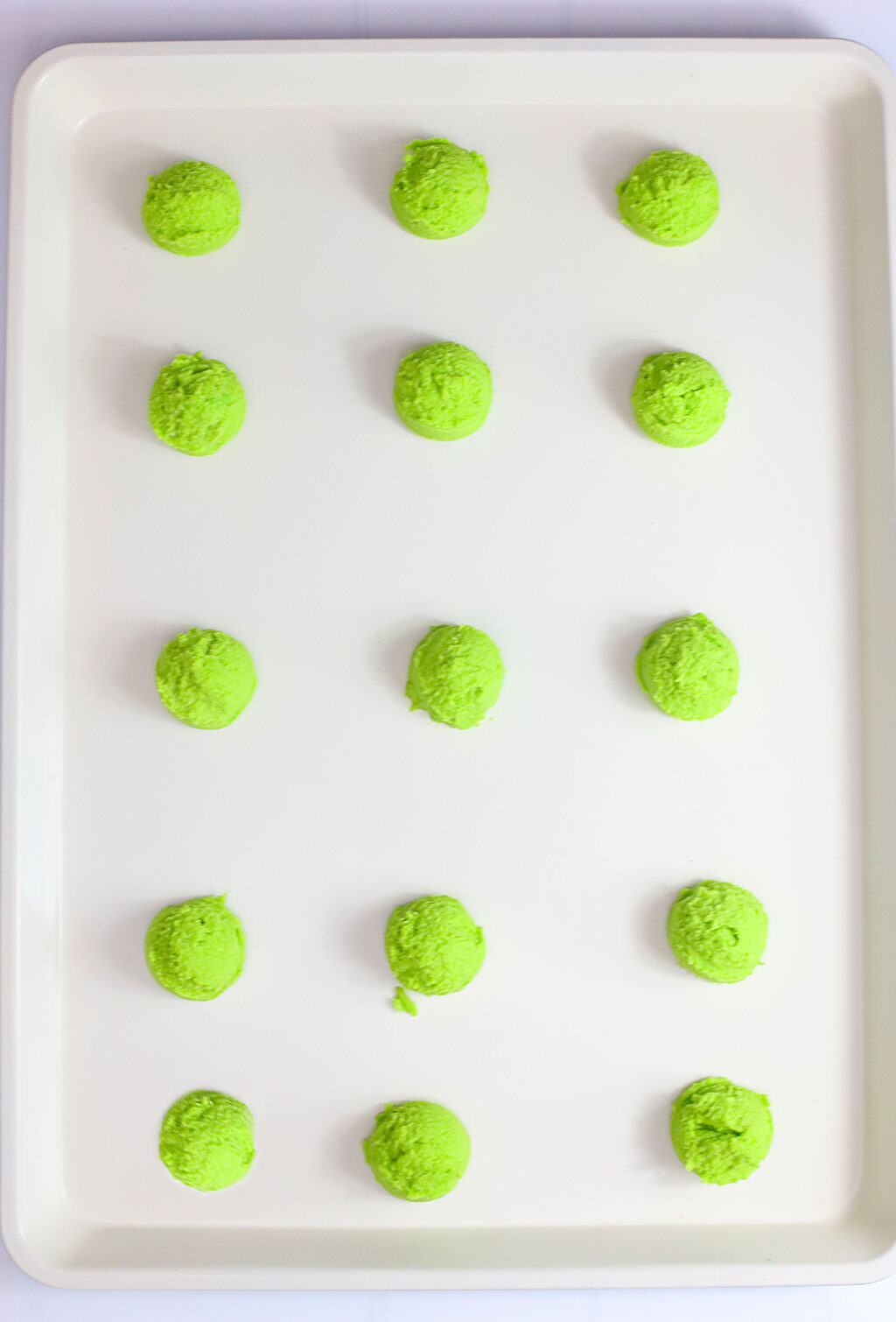 green cookie dough balls on baking sheet