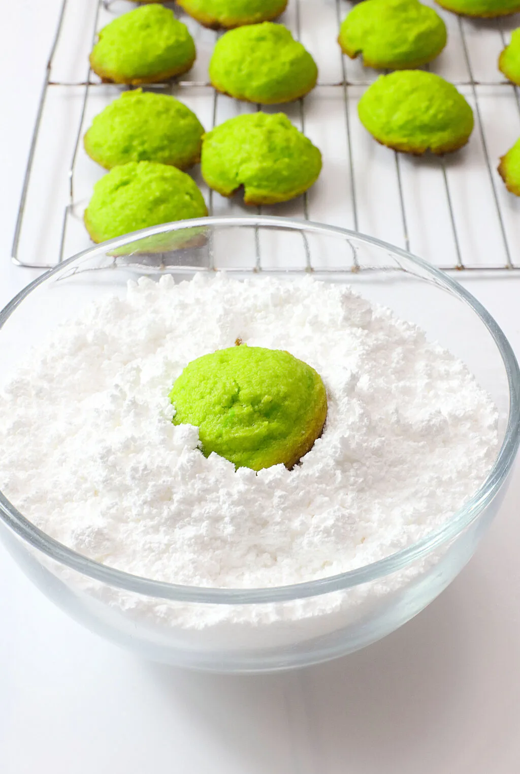 rolling green cookies into powdered sugar