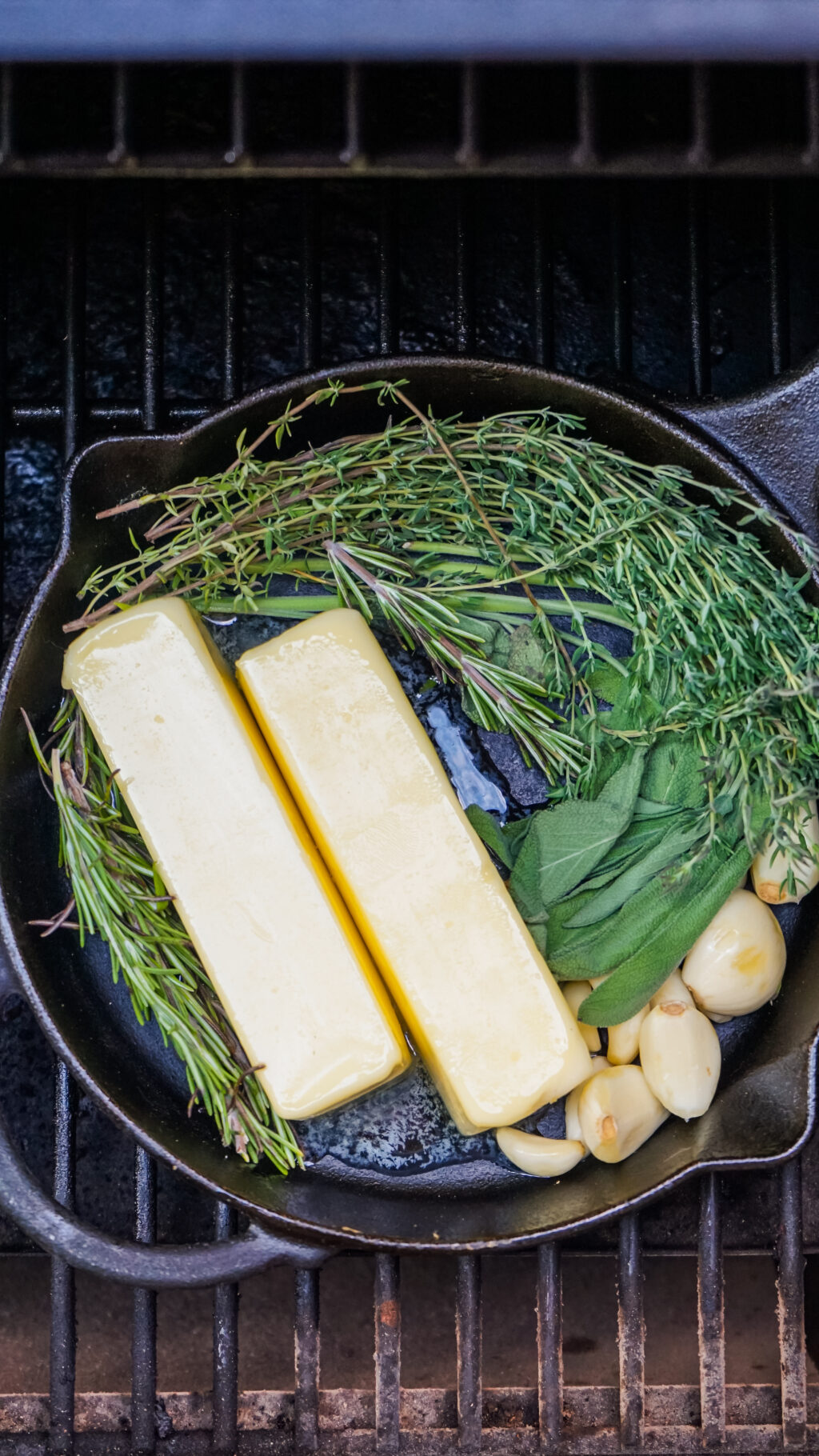 fresh herbs and butter in cast iron pan on grill