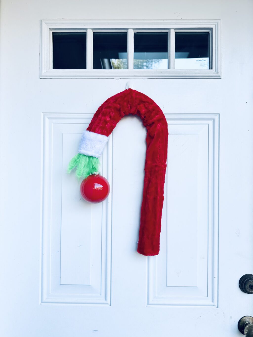 diy grinch wreath made out of dollar tree supplies hanging on white door