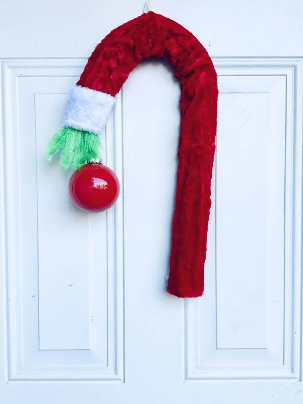 diy grinch wreath hanging on white door