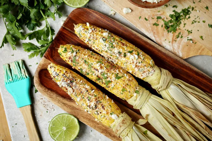 three mexican street corn on the cob on a plate