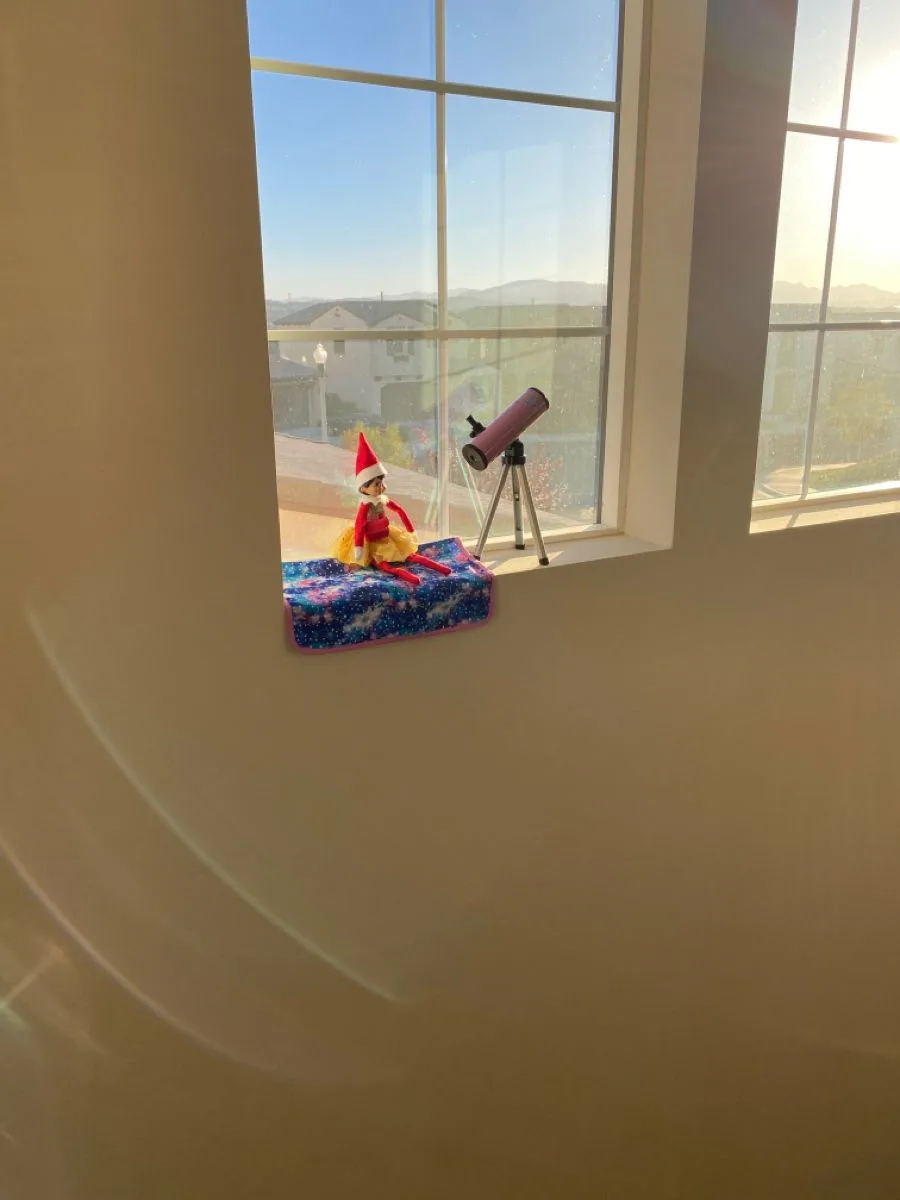 elf in the window with a mini telescope