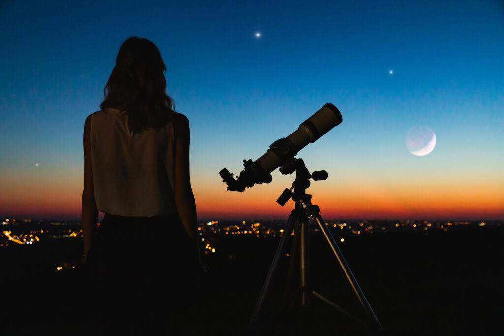 a woman with a telescope stargazing 